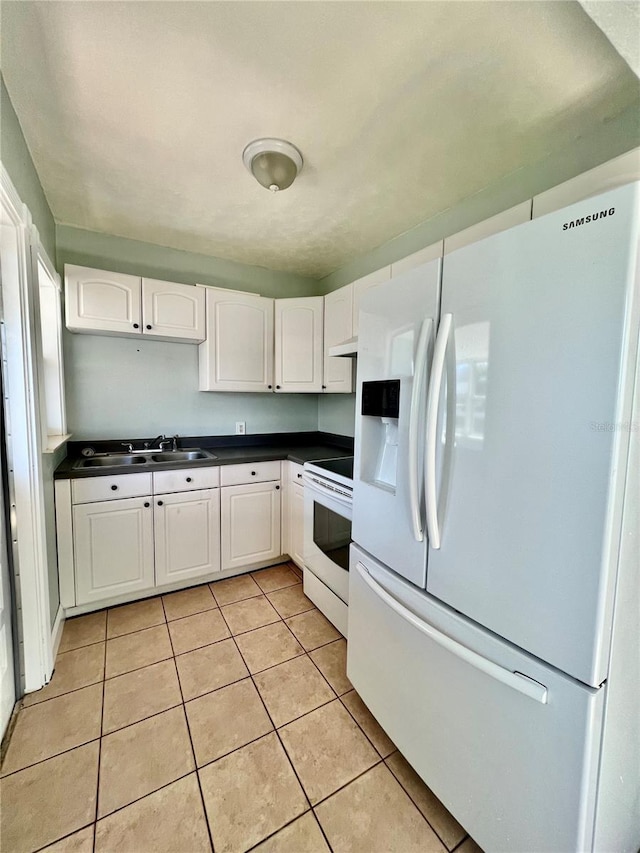 3110 10th Ave N, Saint Petersburg, FL 33713 - kitchen featuring white appliances, dark countertops, light tile patterned flooring, white cabinetry, and under cabinet range hood