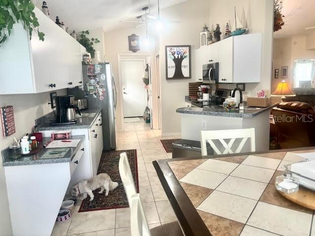 1607 Alexander Crossing Way, Sun City Center, FL 33573 - kitchen with stainless steel microwave, white cabinetry, dark countertops, a ceiling fan, and range
