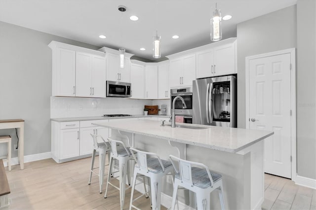 12382 Tibbetts St, Odessa, FL 33556 - kitchen with appliances with stainless steel finishes, white cabinets, a center island with sink, backsplash, and a breakfast bar area