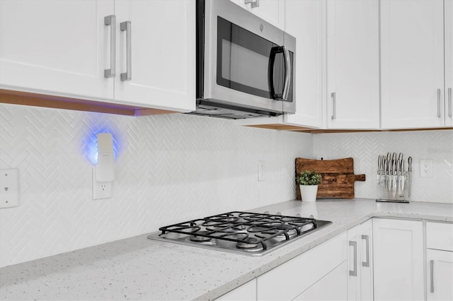 12382 Tibbetts St, Odessa, FL 33556 - kitchen with stainless steel appliances, white cabinetry, decorative backsplash, and light stone counters