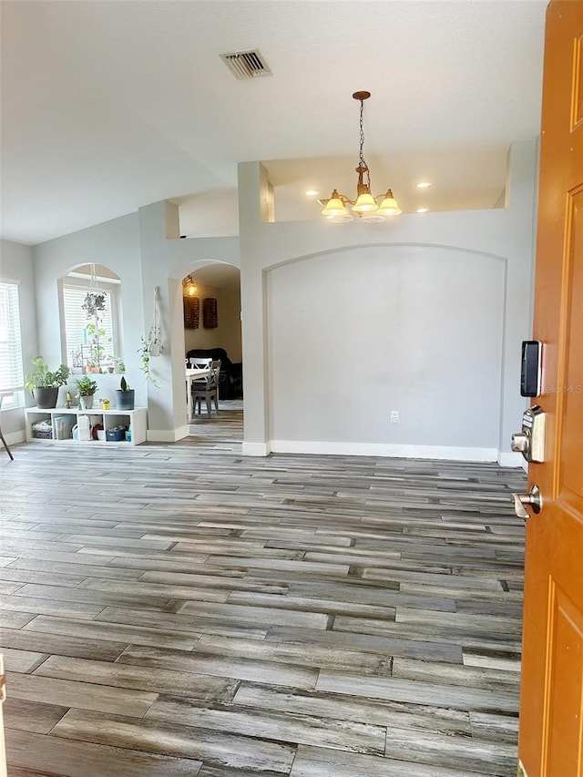 19743 Ellendale Dr, Land O Lakes, FL 34638 - foyer entrance with arched walkways, a chandelier, wood finished floors, and lofted ceiling
