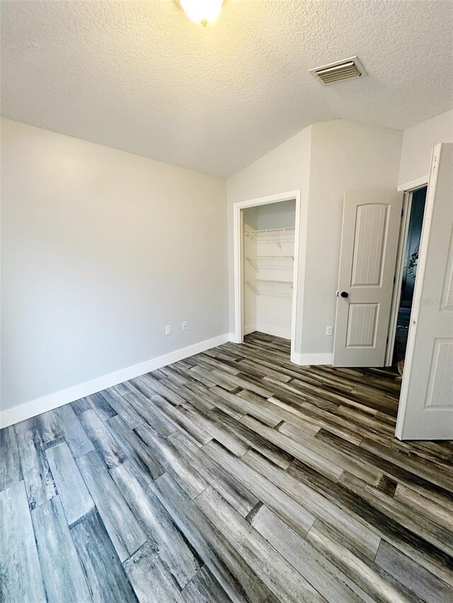19743 Ellendale Dr, Land O Lakes, FL 34638 - unfurnished bedroom with dark wood-type flooring, a closet, a textured ceiling, and vaulted ceiling