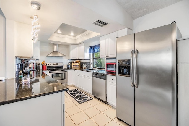1304 Cedar Ct, Tarpon Springs, FL 34689 - kitchen featuring stainless steel appliances, wall chimney range hood, ornamental molding, a tray ceiling, and white cabinets