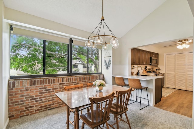4114 Pinelake Ln Unit 202, Tampa, FL 33618 - dining space with light carpet, a chandelier, vaulted ceiling, brick wall, and ceiling fan