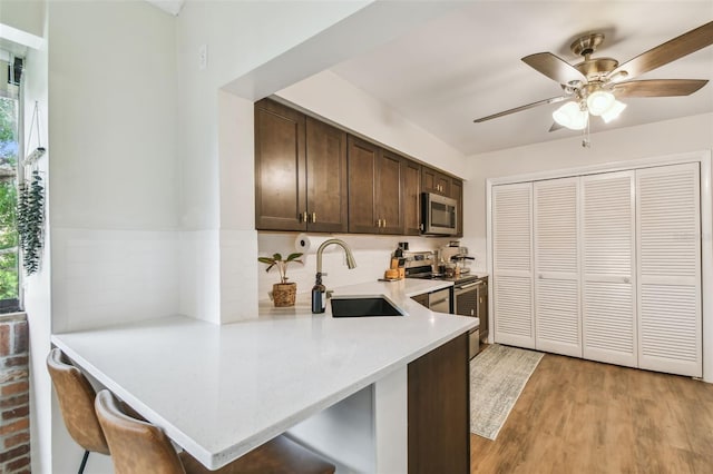 4114 Pinelake Ln Unit 202, Tampa, FL 33618 - kitchen with stainless steel appliances, a ceiling fan, dark brown cabinetry, light countertops, and a breakfast bar area