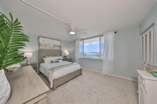 1591 Gulf Blvd Unit 304S, Clearwater Beach, FL 33767 - bedroom featuring a water view, a textured ceiling, ceiling fan, and light carpet