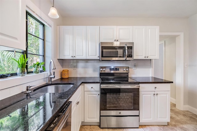 201 W Alva St, Tampa, FL 33603 - kitchen featuring appliances with stainless steel finishes, white cabinetry, decorative backsplash, and dark stone countertops