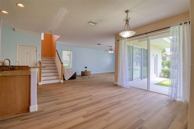 2228 Hannah Way S, Dunedin, FL 34698 - unfurnished living room with light wood-style flooring, stairway, recessed lighting, a textured ceiling, and a ceiling fan