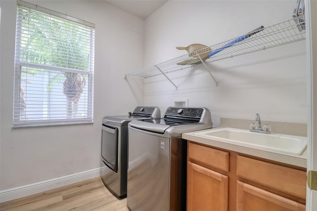 2228 Hannah Way S, Dunedin, FL 34698 - laundry room with separate washer and dryer, light wood-style flooring, and cabinet space