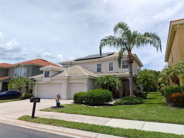 2228 Hannah Way S, Dunedin, FL 34698 - mediterranean / spanish home featuring concrete driveway, a front lawn, roof mounted solar panels, stucco siding, and an attached garage
