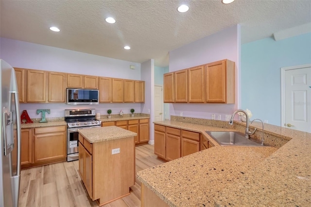 2228 Hannah Way S, Dunedin, FL 34698 - kitchen featuring appliances with stainless steel finishes, light wood finished floors, light stone counters, a textured ceiling, and a peninsula