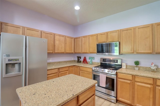 2228 Hannah Way S, Dunedin, FL 34698 - kitchen with stainless steel appliances, light brown cabinetry, a textured ceiling, light stone countertops, and a center island