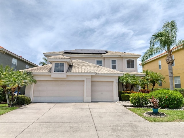 2228 Hannah Way S, Dunedin, FL 34698 - mediterranean / spanish house featuring a garage, a tiled roof, stucco siding, and roof mounted solar panels