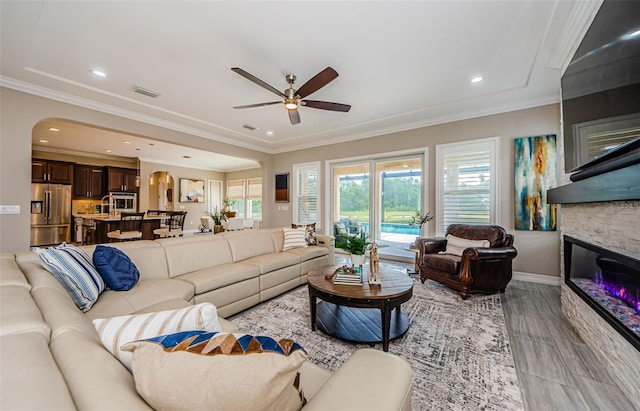 29038 Picana Ln, Wesley Chapel, FL 33543 - living area featuring a ceiling fan, arched walkways, ornamental molding, a fireplace, and recessed lighting