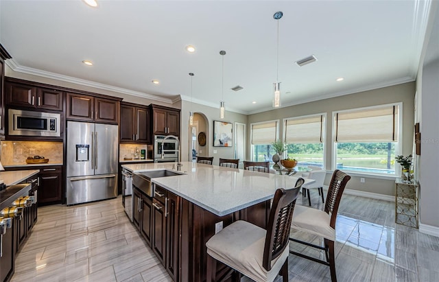 29038 Picana Ln, Wesley Chapel, FL 33543 - kitchen with stainless steel appliances, arched walkways, a kitchen breakfast bar, decorative light fixtures, and decorative backsplash