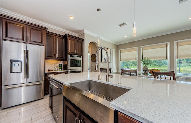 29038 Picana Ln, Wesley Chapel, FL 33543 - kitchen featuring appliances with stainless steel finishes, arched walkways, pendant lighting, tasteful backsplash, and light stone counters