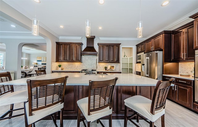 29038 Picana Ln, Wesley Chapel, FL 33543 - kitchen featuring premium range hood, dark brown cabinets, ornamental molding, appliances with stainless steel finishes, and pendant lighting
