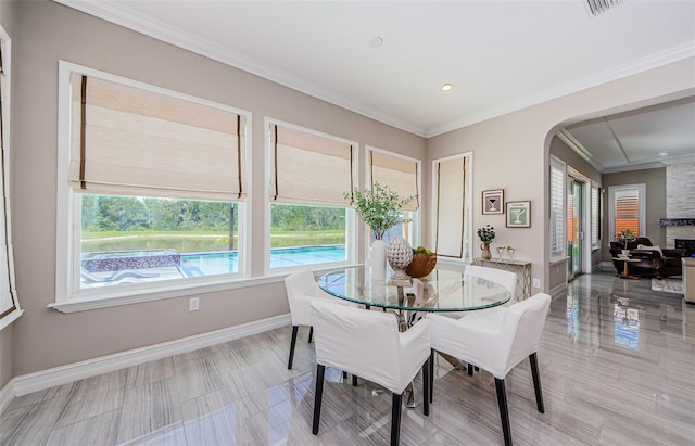 29038 Picana Ln, Wesley Chapel, FL 33543 - dining room featuring plenty of natural light, arched walkways, ornamental molding, and a stone fireplace