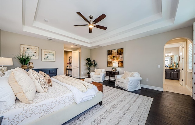 29038 Picana Ln, Wesley Chapel, FL 33543 - bedroom with a raised ceiling, arched walkways, dark wood finished floors, a ceiling fan, and connected bathroom