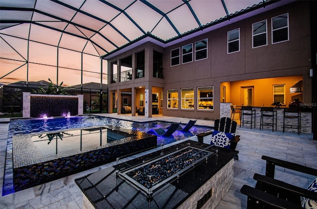 29038 Picana Ln, Wesley Chapel, FL 33543 - back of property at dusk with an in-ground hot tub, a fire pit, a balcony, stucco siding, and a patio