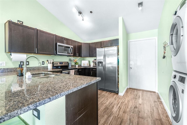 3002 W Cleveland St Unit B9, Tampa, FL 33609 - kitchen with stainless steel appliances, stacked washer and clothes dryer, dark brown cabinets, vaulted ceiling, and light wood-type flooring