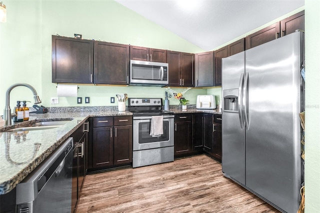3002 W Cleveland St Unit B9, Tampa, FL 33609 - kitchen with stainless steel appliances, lofted ceiling, stone countertops, light wood-style flooring, and dark brown cabinets