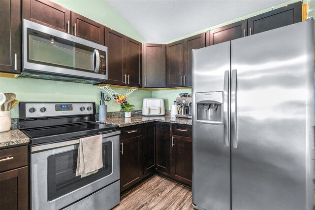 3002 W Cleveland St Unit B9, Tampa, FL 33609 - kitchen featuring appliances with stainless steel finishes, lofted ceiling, light wood-style floors, stone countertops, and dark brown cabinets