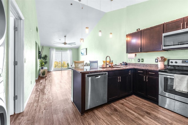 3002 W Cleveland St Unit B9, Tampa, FL 33609 - kitchen featuring stainless steel appliances, dark wood-style floors, a peninsula, dark stone countertops, and high vaulted ceiling