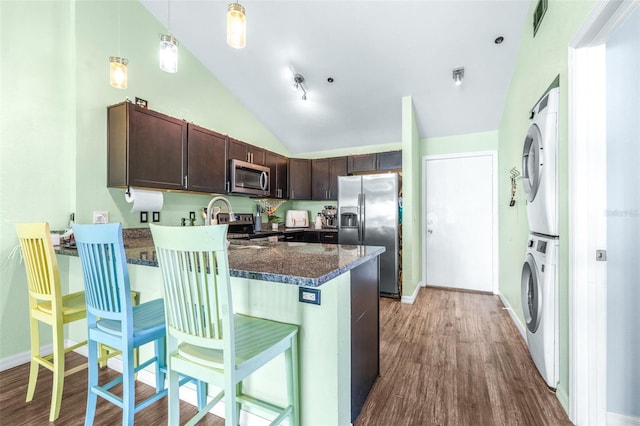3002 W Cleveland St Unit B9, Tampa, FL 33609 - kitchen featuring stainless steel appliances, stacked washer and clothes dryer, dark brown cabinetry, a peninsula, and wood finished floors