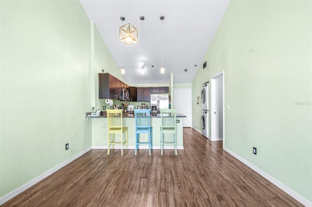 3002 W Cleveland St Unit B9, Tampa, FL 33609 - kitchen featuring stainless steel appliances, estacked washer and dryer, dark wood-style flooring, a peninsula, and high vaulted ceiling