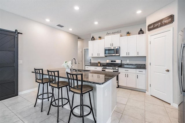 9839 Lemon Drop Loop, Sun City Center, FL 33573 - kitchen with appliances with stainless steel finishes, a breakfast bar area, white cabinetry, an island with sink, and light tile patterned floors