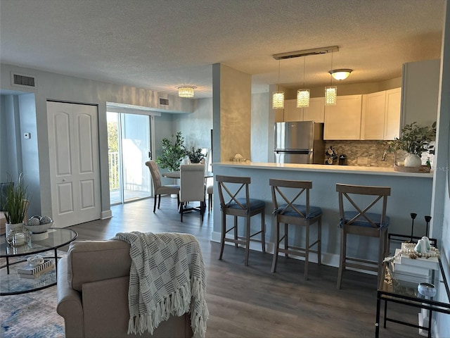3315 58th Ave S Unit 421, Saint Petersburg, FL 33712 - kitchen featuring freestanding refrigerator, a textured ceiling, dark wood-type flooring, decorative backsplash, and white cabinetry