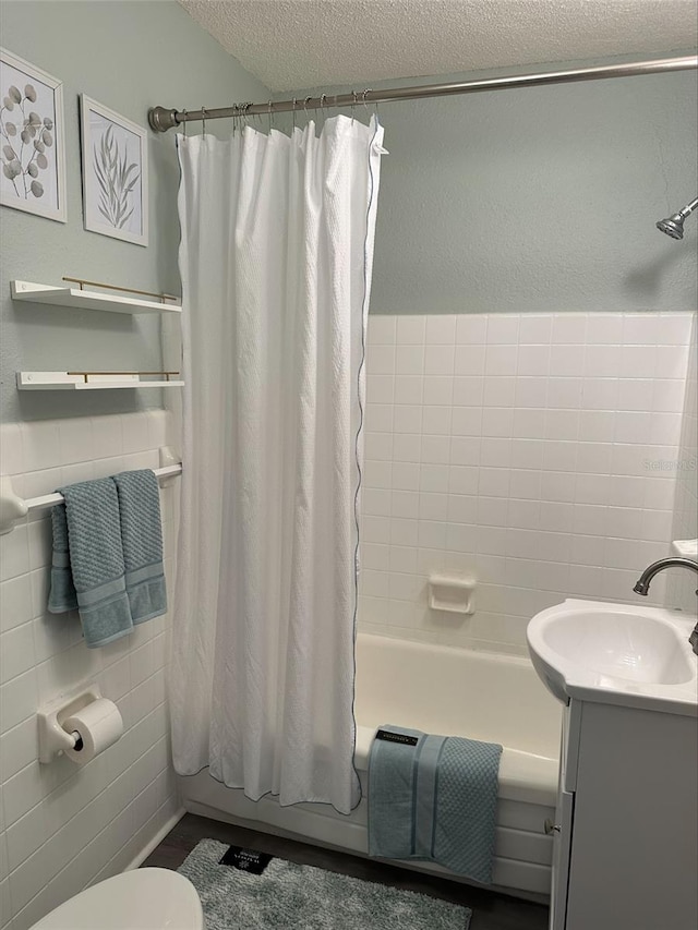 3315 58th Ave S Unit 421, Saint Petersburg, FL 33712 - bathroom with shower / tub combo with curtain, vanity, a textured ceiling, and tile walls