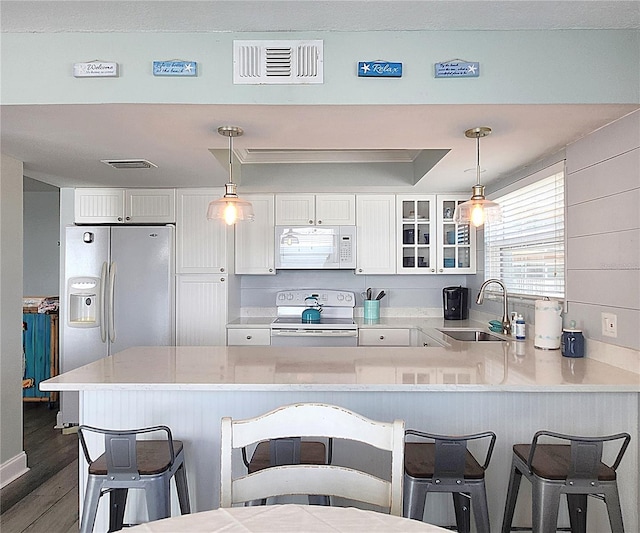 18650 Gulf Blvd Unit 314, Indian Shores, FL 33785 - kitchen with white appliances, a peninsula, glass insert cabinets, dark wood-type flooring, and white cabinetry
