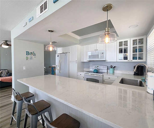 18650 Gulf Blvd Unit 314, Indian Shores, FL 33785 - kitchen featuring white appliances, a peninsula, light stone countertops, a breakfast bar area, and ornamental molding