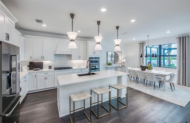 16423 Sapphire Point Dr, Lakewood Ranch, FL 34211 - kitchen with high end refrigerator, custom exhaust hood, dark wood-style floors, black gas cooktop, and white cabinetry
