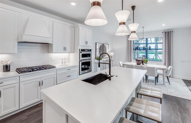16423 Sapphire Point Dr, Lakewood Ranch, FL 34211 - kitchen featuring gas stovetop, double oven, custom exhaust hood, dark wood finished floors, and recessed lighting