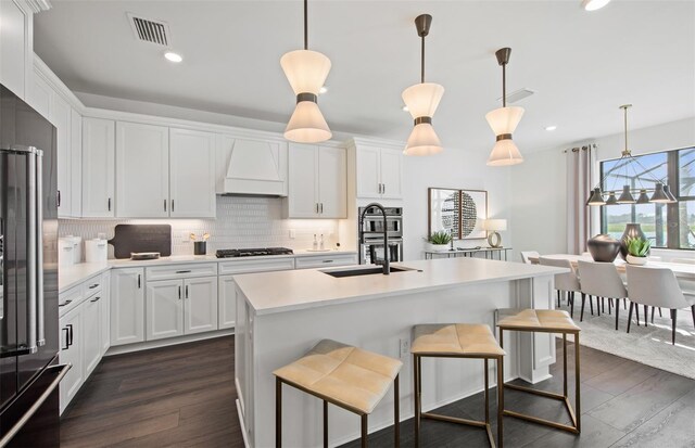 16423 Sapphire Point Dr, Lakewood Ranch, FL 34211 - kitchen with custom range hood, white cabinets, appliances with stainless steel finishes, backsplash, and recessed lighting