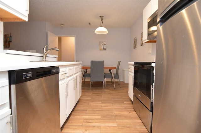 10265 Gandy Blvd N Unit 1409, Saint Petersburg, FL 33702 - kitchen with appliances with stainless steel finishes, white cabinets, light wood-style flooring, and light countertops