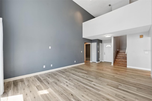 428 Klosterman Rd W, W, Palm Harbor, FL 34683 - unfurnished living room with a towering ceiling, stairs, and light wood-type flooring