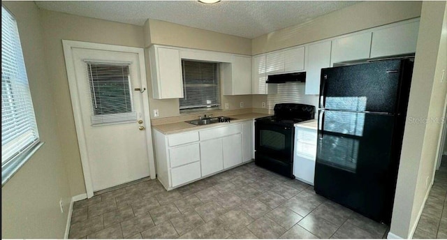 102,106,110,202,204 N Jasper Street 102,106,110,202,204, Bushnell, FL 33513 - kitchen featuring black appliances, under cabinet range hood, light countertops, white cabinets, and a textured ceiling