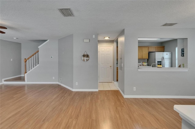 3455 Castle Stone Ct, Valrico, FL 33594 - unfurnished living room featuring light wood-style floors, a ceiling fan, stairway, and a textured ceiling