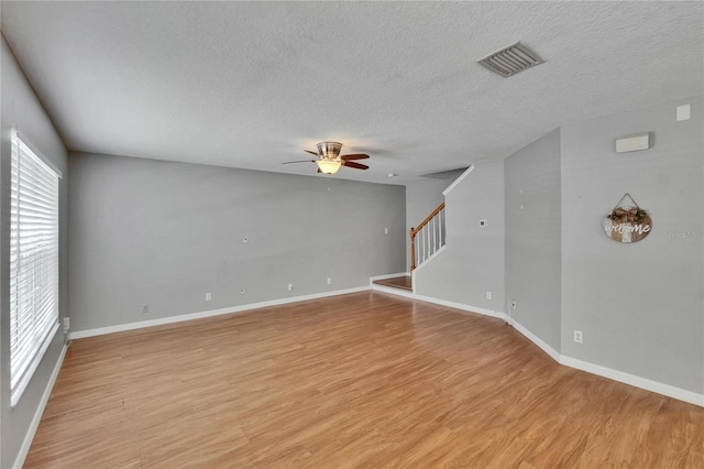 3455 Castle Stone Ct, Valrico, FL 33594 - empty room featuring ceiling fan, light wood finished floors, a textured ceiling, and stairs