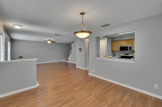 3455 Castle Stone Ct, Valrico, FL 33594 - unfurnished living room featuring light wood-style floors, a ceiling fan, stairs, and a textured ceiling