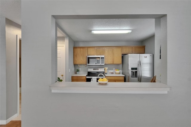 3455 Castle Stone Ct, Valrico, FL 33594 - kitchen with stainless steel appliances, light countertops, a peninsula, and a textured ceiling
