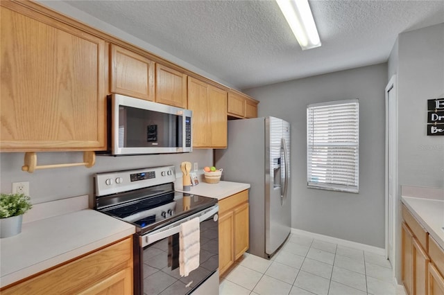 3455 Castle Stone Ct, Valrico, FL 33594 - kitchen featuring stainless steel appliances, a textured ceiling, light countertops, light tile patterned flooring, and light brown cabinets
