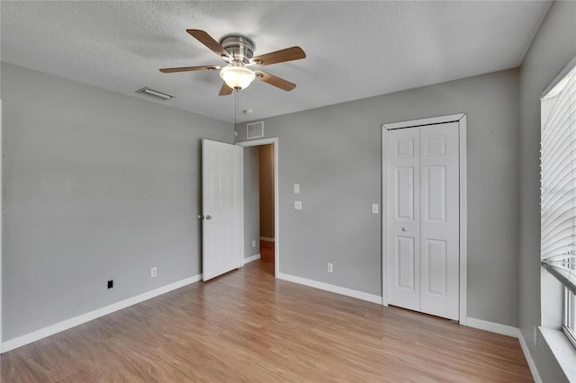 3455 Castle Stone Ct, Valrico, FL 33594 - unfurnished bedroom featuring light wood finished floors, a closet, a textured ceiling, and a ceiling fan
