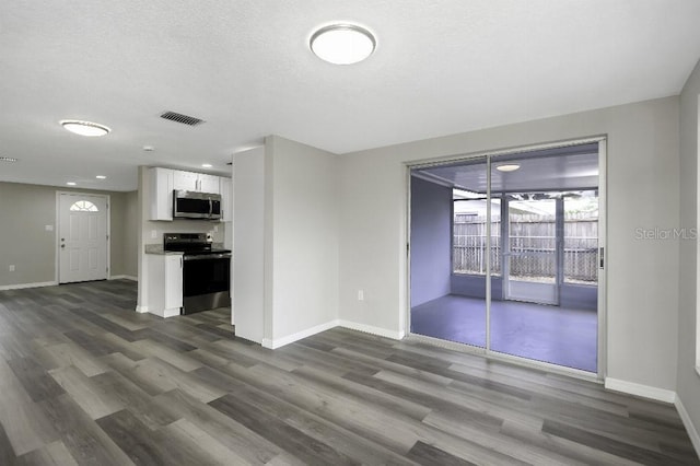7625 Marechal Ave, Port Richey, FL 34668 - unfurnished living room with dark wood-style flooring, a textured ceiling, and recessed lighting