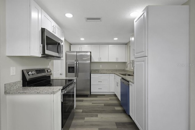 7625 Marechal Ave, Port Richey, FL 34668 - kitchen featuring appliances with stainless steel finishes, white cabinetry, light stone counters, and recessed lighting