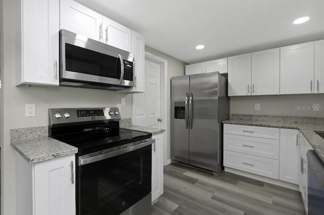 7625 Marechal Ave, Port Richey, FL 34668 - kitchen with stainless steel appliances, white cabinetry, recessed lighting, light stone counters, and wood finished floors